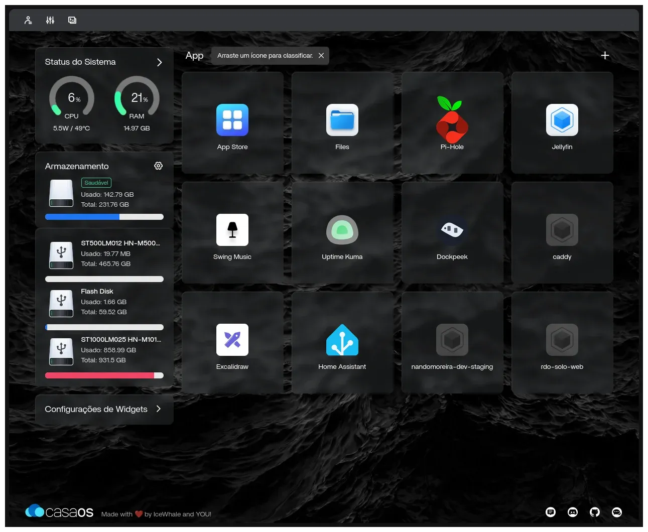 Painel do CasaOS com CPU a 6% (5,5 W, 49 °C), RAM a 21%, o SSD interno com 142,79 GB usados de 231,76 GB, três discos USB (um HD de 500 GB, um pendrive de 64 GB e um HD de 1 TB quase cheio) e a grade de apps: Pi-hole, Jellyfin, Swing Music, Uptime Kuma, Dockpeek, Caddy, Excalidraw, Home Assistant, a homologação do site e o rdo-solo-web.